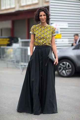 Желтая футболка с круглым вырезом с цветочным принтом и черная длинная юбка со складками — хорошая формула для создания модного и удобного образа.